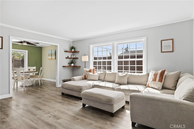 living room with light wood finished floors, ornamental molding, and baseboards