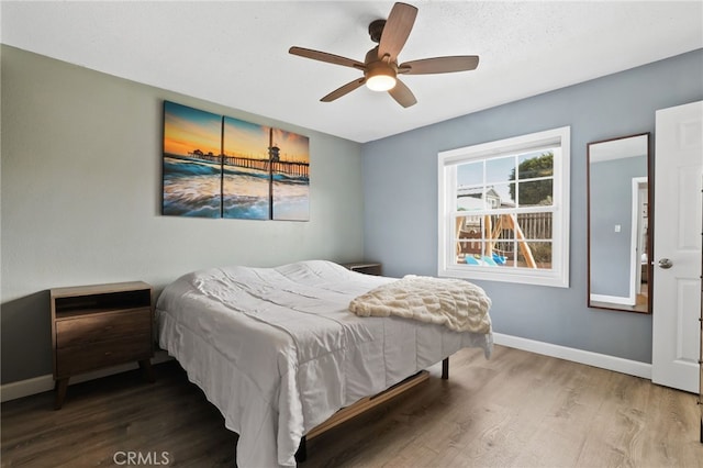 bedroom featuring a ceiling fan, baseboards, and wood finished floors