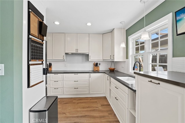 kitchen with dark countertops, a sink, and white cabinets