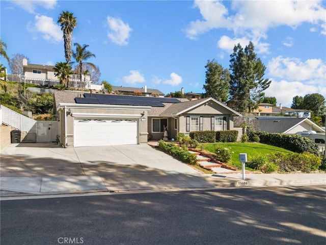 single story home with an attached garage, fence, driveway, a gate, and roof mounted solar panels