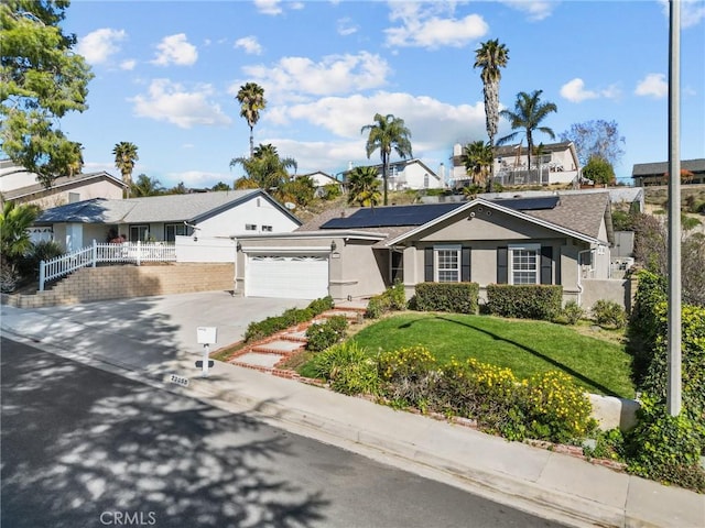 ranch-style house with driveway, solar panels, an attached garage, fence, and stucco siding