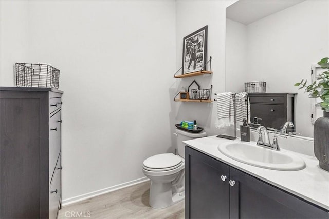 bathroom with toilet, wood finished floors, vanity, and baseboards