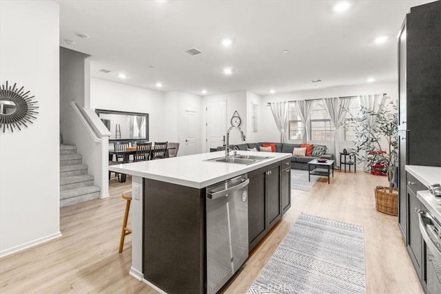 kitchen with a center island with sink, visible vents, open floor plan, a sink, and dishwasher