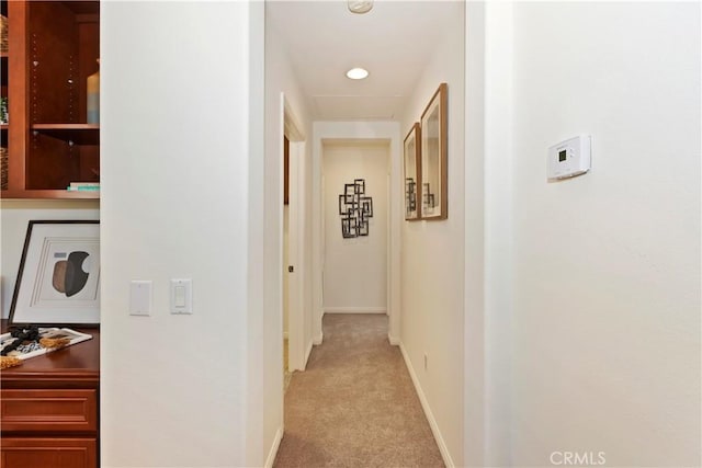 corridor featuring baseboards and light colored carpet