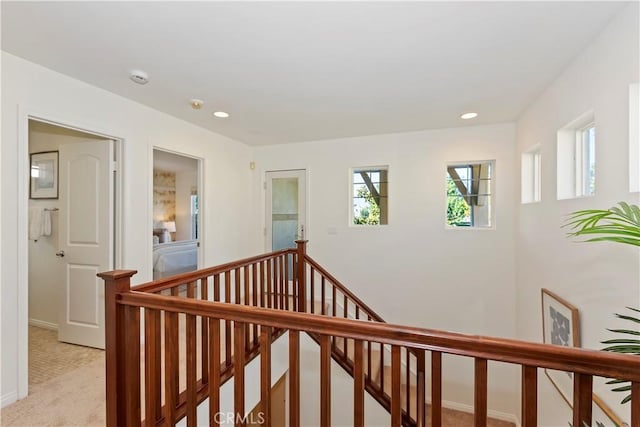 hallway with recessed lighting, light colored carpet, and an upstairs landing