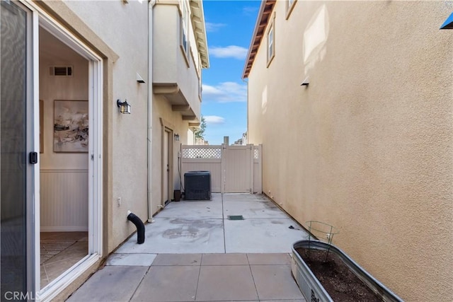 view of patio with a gate, visible vents, fence, and central AC