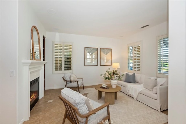 living room featuring a glass covered fireplace, visible vents, and baseboards