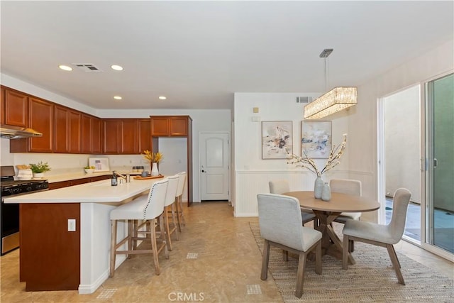 kitchen featuring light countertops, stainless steel range with gas stovetop, visible vents, and a kitchen island with sink