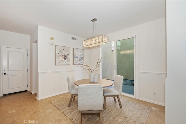 dining space with wainscoting, visible vents, and a notable chandelier