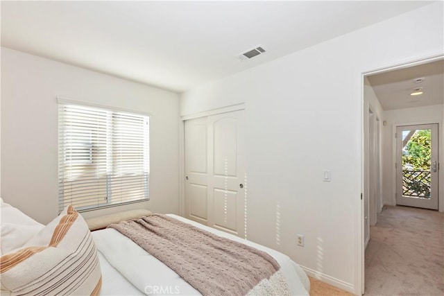 bedroom with a closet, visible vents, and light carpet