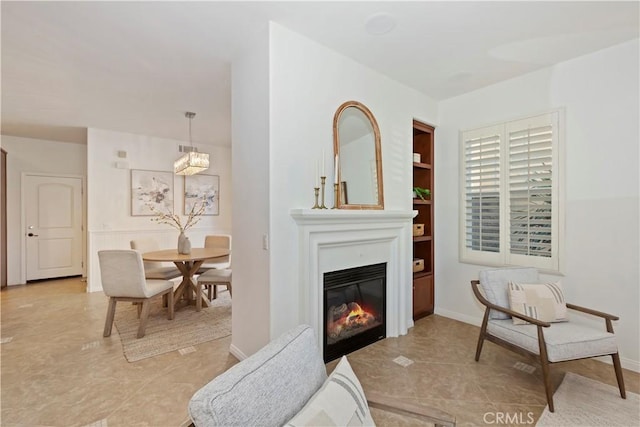 interior space with built in shelves, a glass covered fireplace, and baseboards