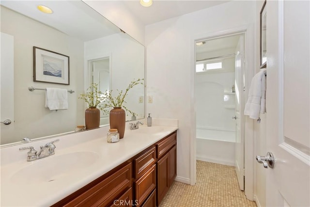 full bath featuring baseboards, double vanity, a sink, and tile patterned floors