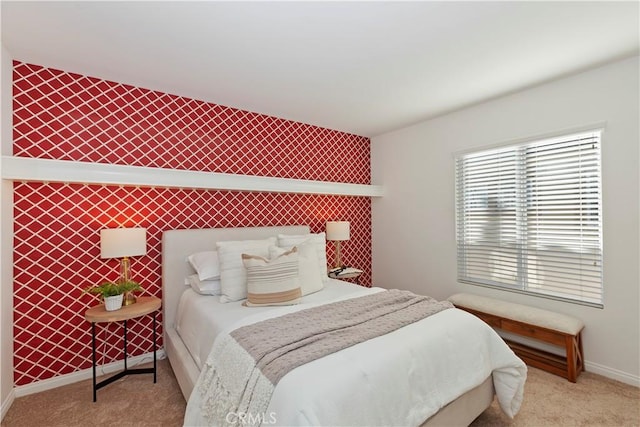 bedroom featuring wallpapered walls, carpet, an accent wall, and baseboards