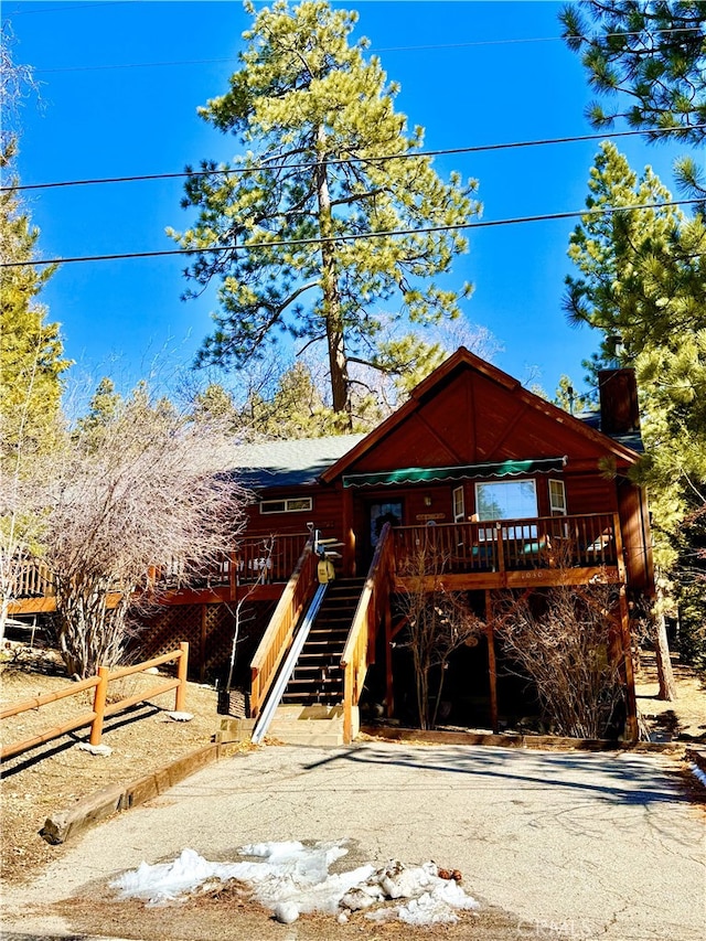 view of front facade featuring a deck, stairway, and a chimney