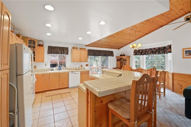 kitchen featuring light tile patterned flooring, light brown cabinets, white appliances, a sink, and glass insert cabinets