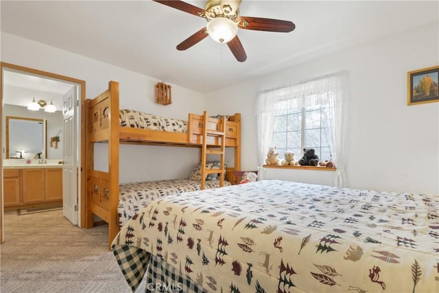 bedroom with connected bathroom, light carpet, a sink, and a ceiling fan