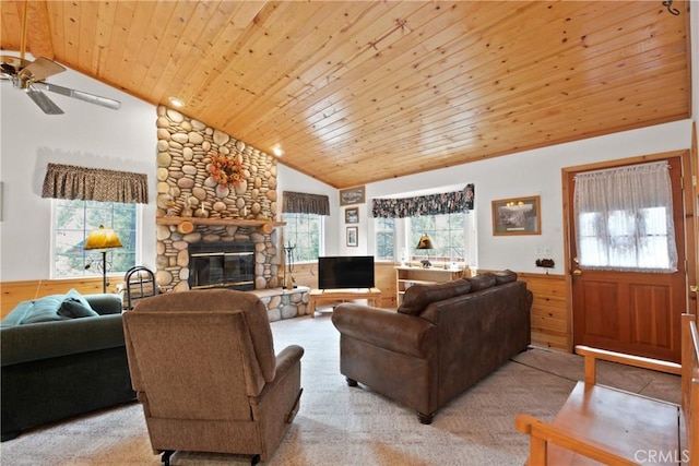 living room with a wealth of natural light, wooden ceiling, wainscoting, and a stone fireplace