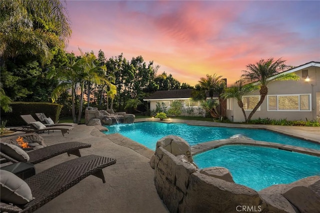 pool with a patio and an in ground hot tub