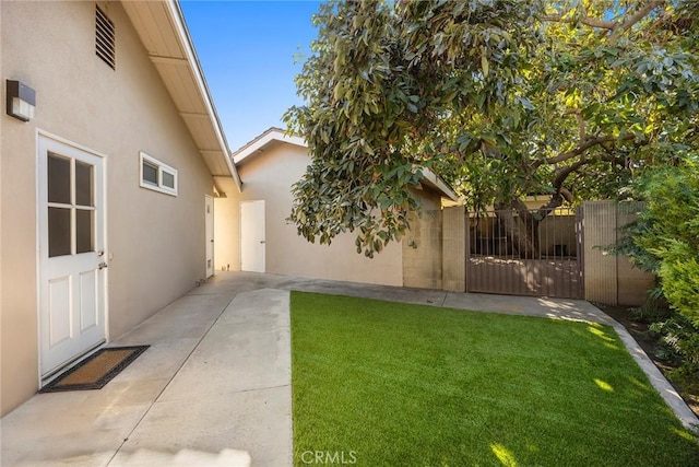 view of yard featuring a patio area, fence, and a gate