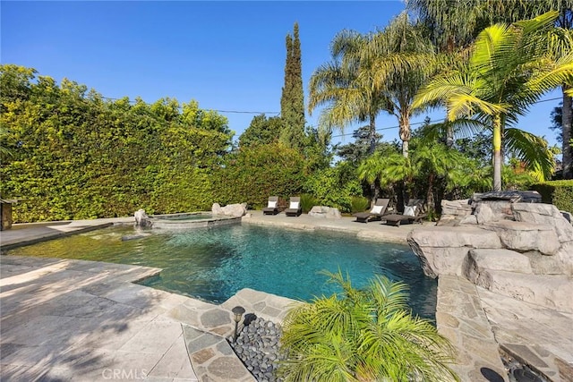 view of swimming pool featuring a pool with connected hot tub and a patio area