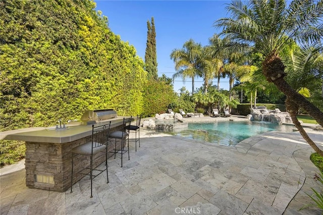 view of pool with a patio area, outdoor dry bar, area for grilling, and a pool with connected hot tub