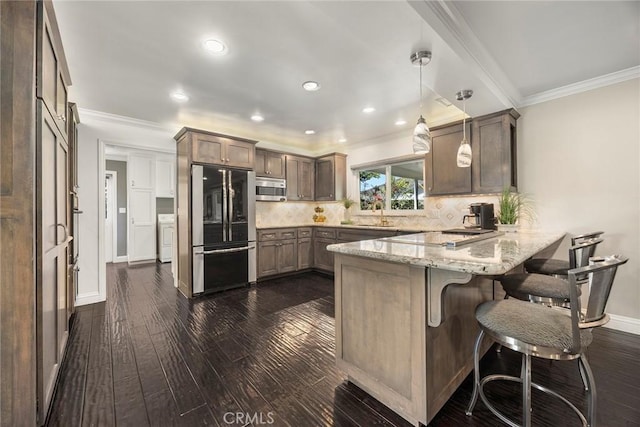 kitchen featuring stainless steel appliances, backsplash, crown molding, and a peninsula