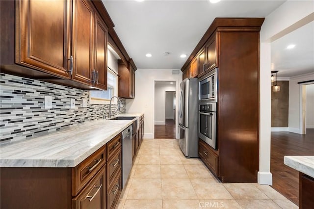 kitchen featuring baseboards, decorative backsplash, stainless steel appliances, a sink, and light tile patterned flooring