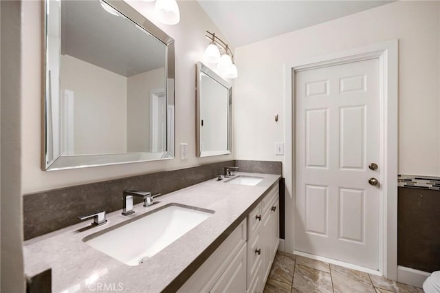 full bath featuring double vanity, marble finish floor, and a sink