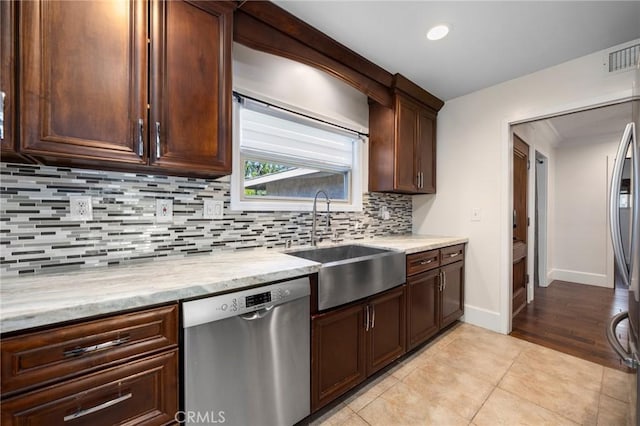 kitchen featuring light tile patterned floors, visible vents, decorative backsplash, a sink, and dishwasher