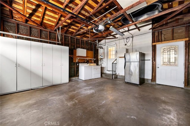 garage featuring a garage door opener, water heater, washer and clothes dryer, and freestanding refrigerator