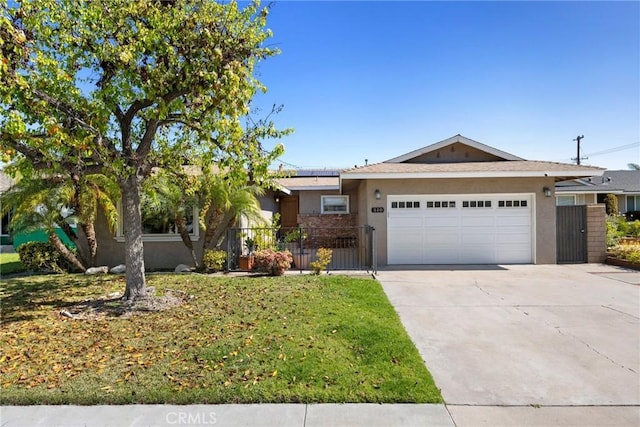 ranch-style home featuring a garage, fence, concrete driveway, roof mounted solar panels, and stucco siding