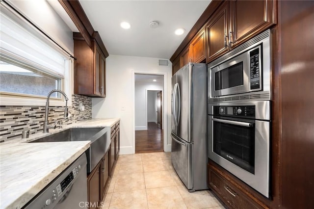 kitchen with light stone counters, light tile patterned floors, tasteful backsplash, visible vents, and appliances with stainless steel finishes