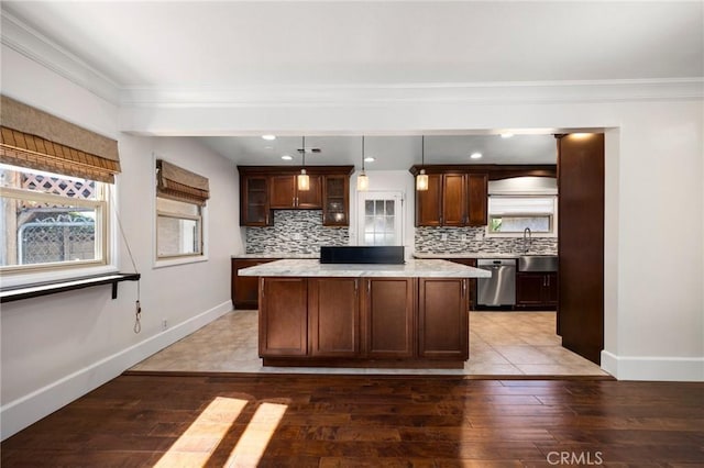 kitchen with light wood-type flooring, a kitchen island, backsplash, and stainless steel dishwasher