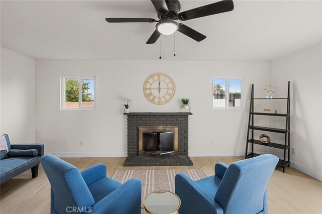 living area featuring a fireplace, wood finished floors, a ceiling fan, and baseboards