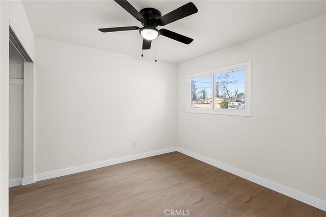 unfurnished bedroom with a ceiling fan, a closet, baseboards, and wood finished floors