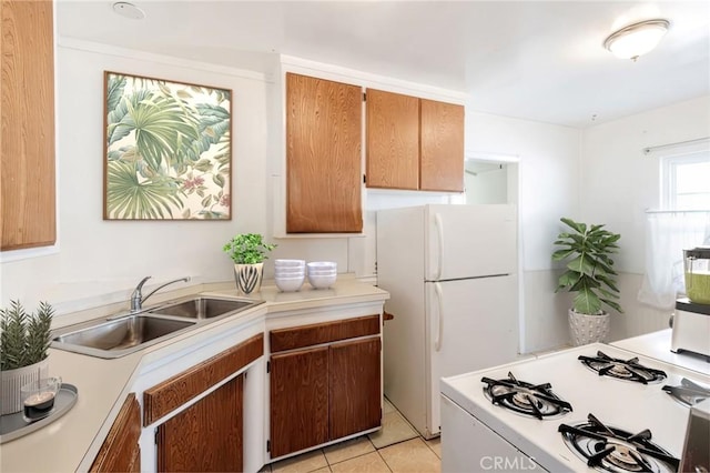 kitchen featuring white appliances, light countertops, a sink, and light tile patterned floors