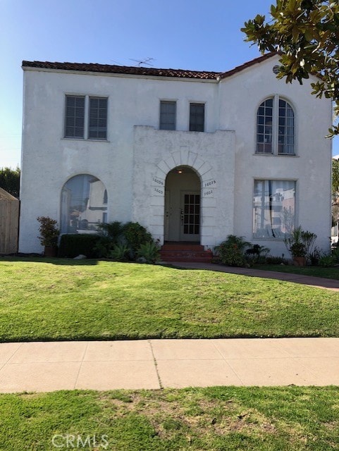 mediterranean / spanish home featuring stucco siding, fence, and a front yard