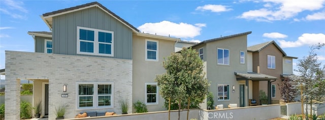 rear view of property featuring board and batten siding and brick siding