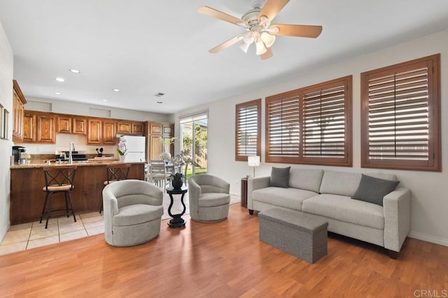 living room with light wood-style floors, ceiling fan, baseboards, and recessed lighting