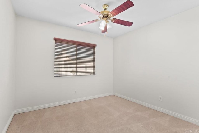 carpeted spare room with a ceiling fan and baseboards