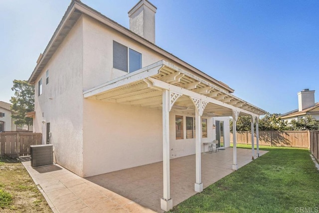 back of house featuring central AC unit, a fenced backyard, a yard, stucco siding, and a patio area