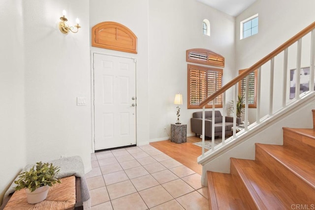 entrance foyer with baseboards, stairway, a towering ceiling, and light tile patterned floors