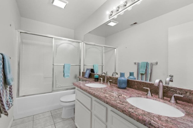 bathroom with double vanity, a sink, toilet, and tile patterned floors