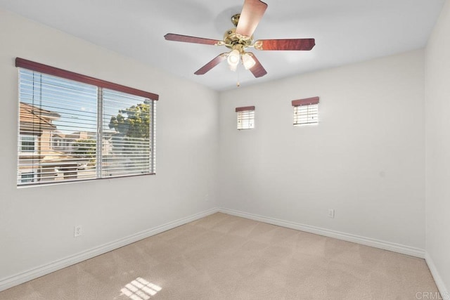 empty room with light carpet, ceiling fan, and baseboards