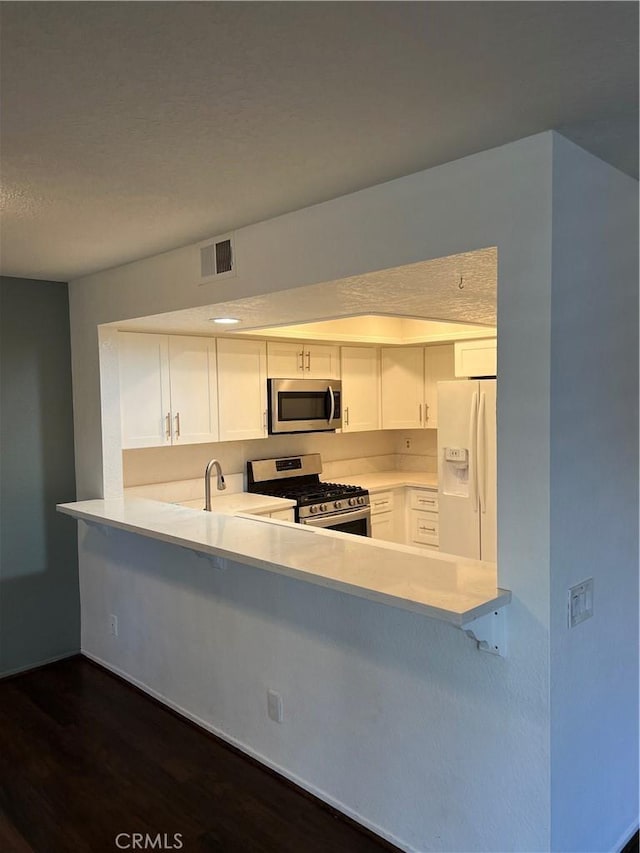 kitchen with visible vents, white cabinets, a peninsula, stainless steel appliances, and light countertops