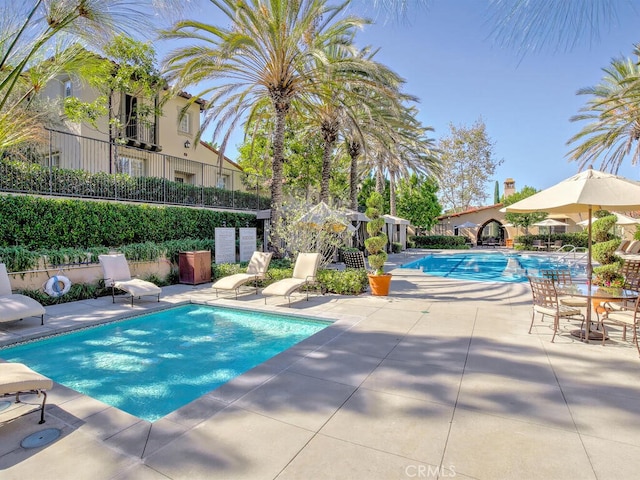 community pool with a patio and fence