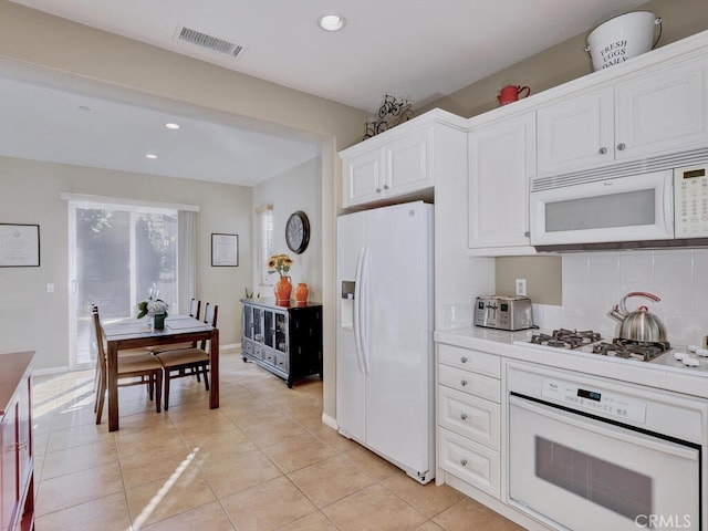 kitchen with light tile patterned floors, white appliances, visible vents, white cabinets, and light countertops