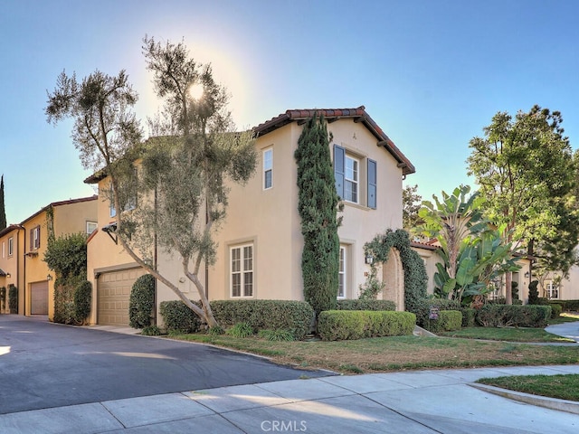 view of side of property with a tile roof, driveway, an attached garage, and stucco siding