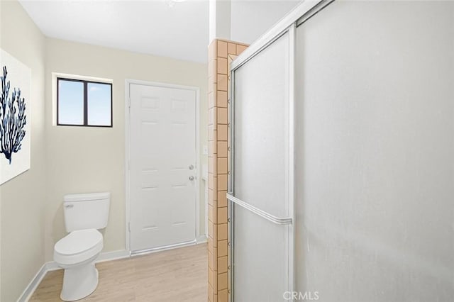 full bath featuring baseboards, a shower with shower door, toilet, and wood finished floors