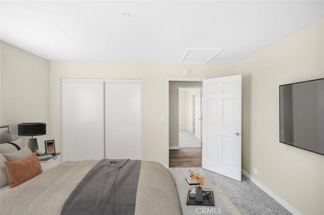 carpeted bedroom with a closet, attic access, and baseboards